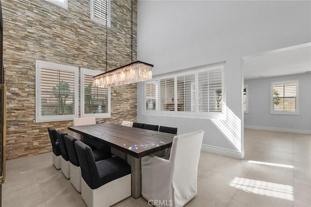 tiled dining area featuring a high ceiling and a chandelier