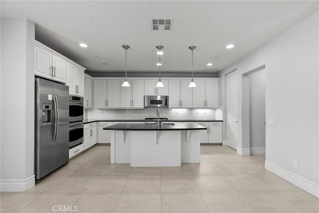 kitchen with white cabinets, a breakfast bar, stainless steel appliances, and a kitchen island with sink