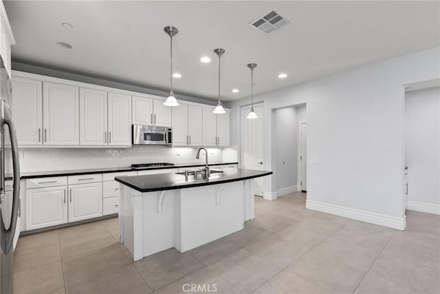 kitchen with stainless steel appliances, sink, decorative light fixtures, a center island with sink, and white cabinetry