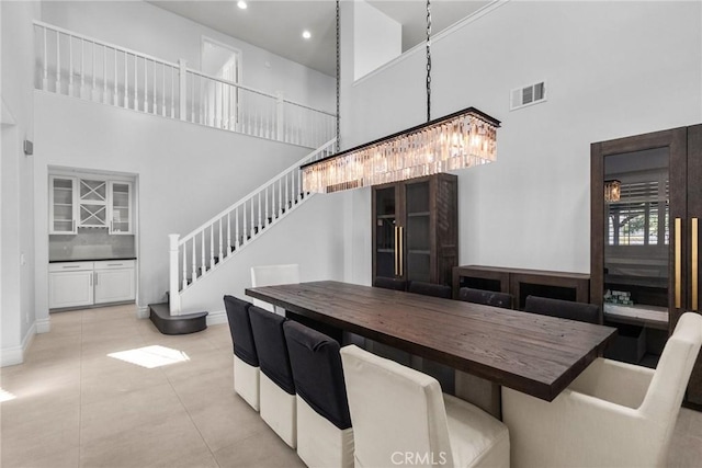 tiled dining room with a chandelier and a towering ceiling