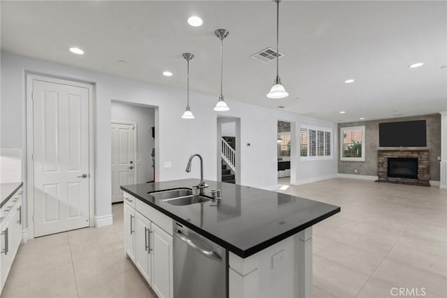 kitchen featuring white cabinetry, sink, hanging light fixtures, stainless steel dishwasher, and a fireplace