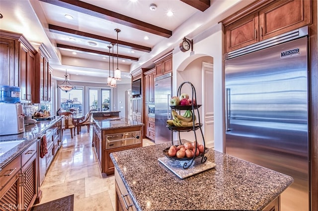 kitchen featuring stainless steel built in fridge, hanging light fixtures, beam ceiling, and a kitchen island