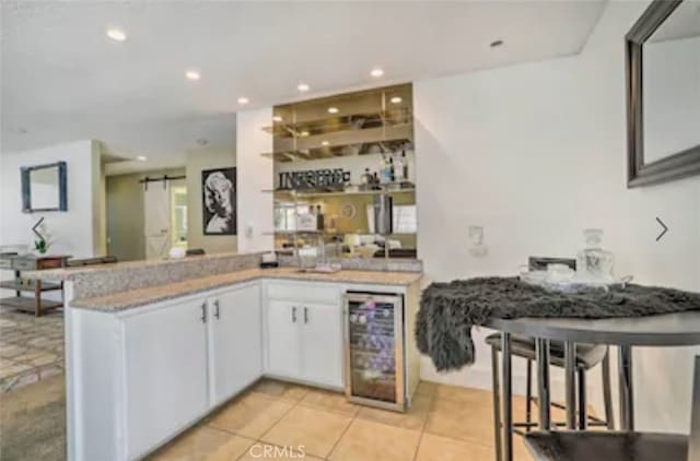 bar featuring white cabinets, a barn door, light tile patterned flooring, and beverage cooler