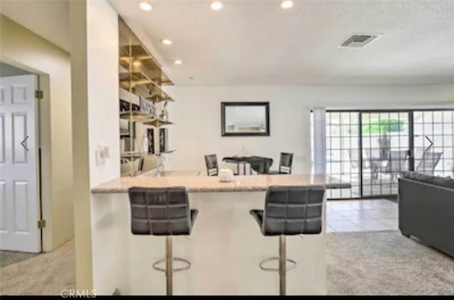 kitchen with light carpet, kitchen peninsula, and a kitchen bar