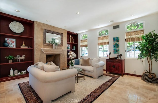 sitting room with a fireplace, built in features, and a healthy amount of sunlight