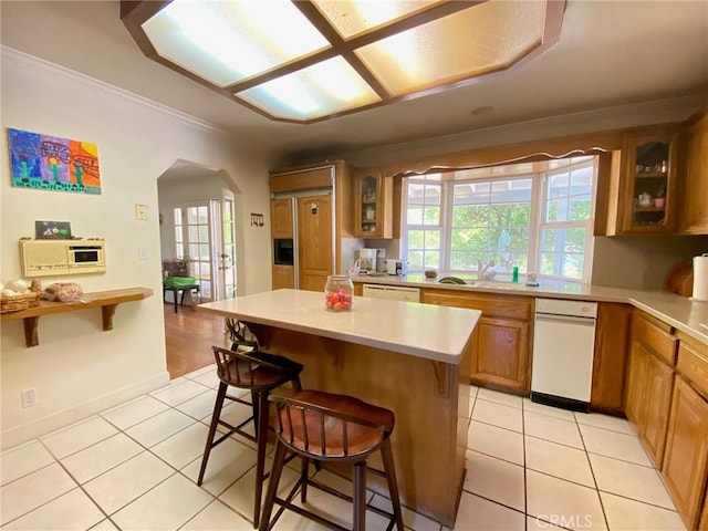 kitchen with a kitchen island, ornamental molding, a breakfast bar area, and light tile patterned floors