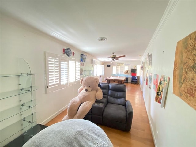 living room featuring ceiling fan, ornamental molding, and light hardwood / wood-style flooring