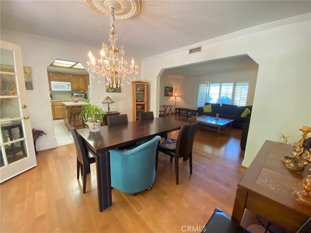 dining room with a chandelier, light hardwood / wood-style flooring, and ornamental molding