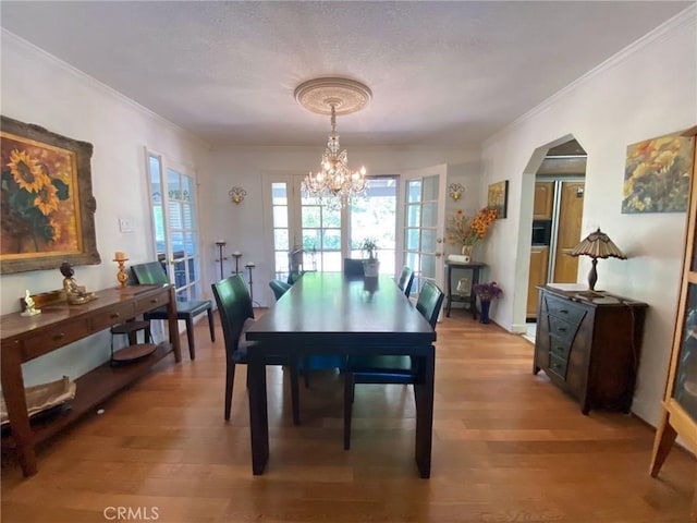 dining area with hardwood / wood-style floors, a textured ceiling, an inviting chandelier, and ornamental molding