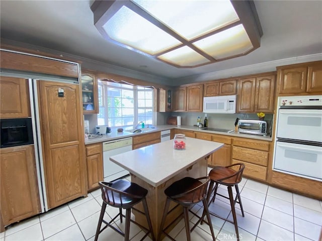 kitchen featuring a kitchen bar, ornamental molding, white appliances, light tile patterned floors, and a center island