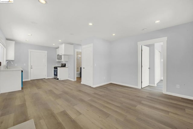 unfurnished living room with light hardwood / wood-style flooring and sink