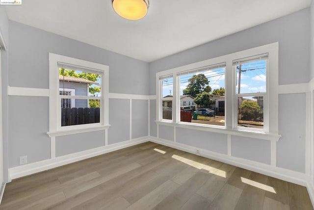 unfurnished room with wood-type flooring and a healthy amount of sunlight