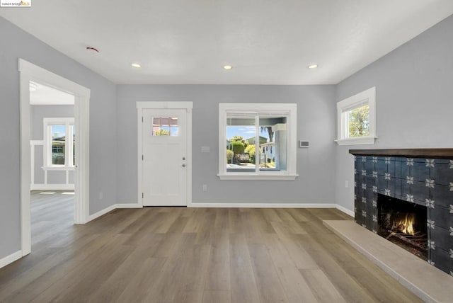 foyer entrance with light wood-type flooring and a tile fireplace