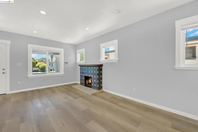 unfurnished living room with light wood-type flooring and a tile fireplace