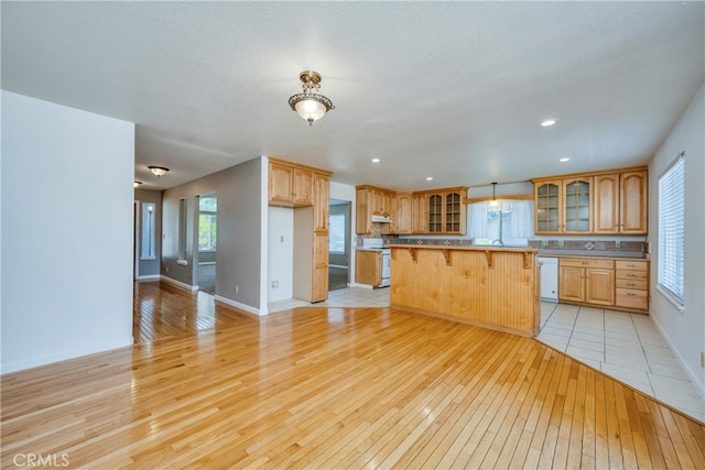 kitchen with light wood-type flooring, white appliances, a center island, and a kitchen bar