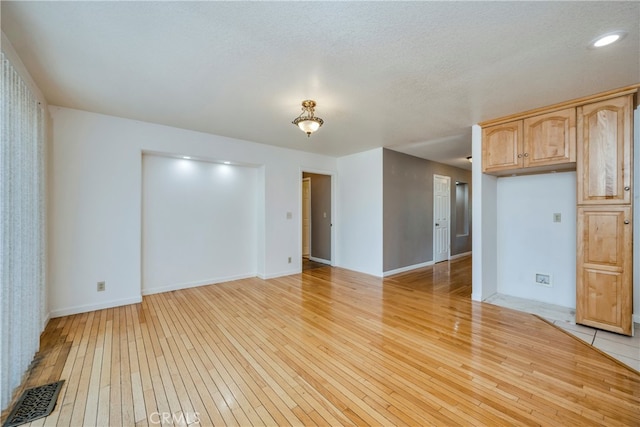 unfurnished room featuring a textured ceiling and light hardwood / wood-style floors