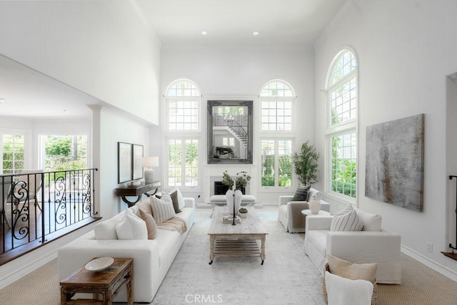 living room featuring a healthy amount of sunlight, light colored carpet, and a high ceiling