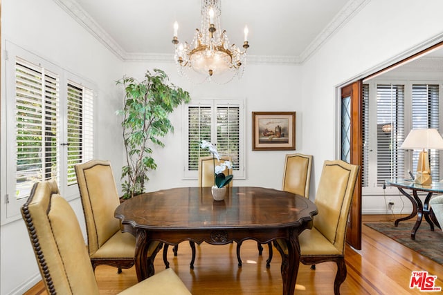 dining room with ornamental molding, hardwood / wood-style flooring, and a notable chandelier