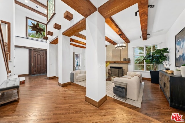 foyer entrance featuring a notable chandelier, wood-type flooring, beamed ceiling, and a fireplace