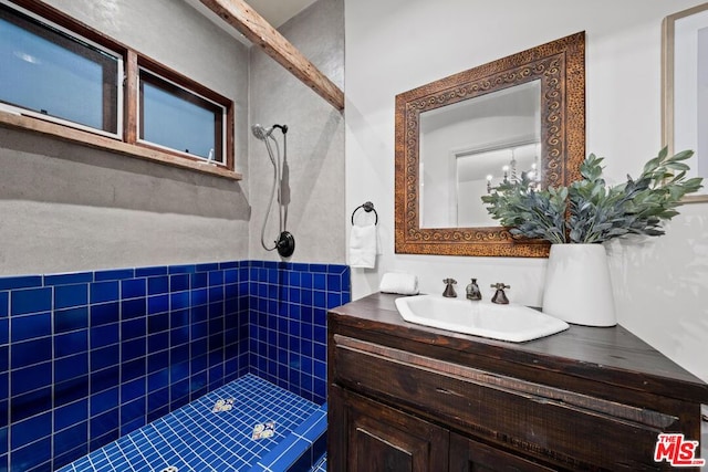 bathroom with a tile shower and vanity