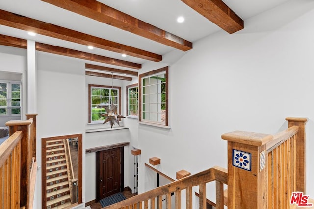 hall featuring beamed ceiling and plenty of natural light