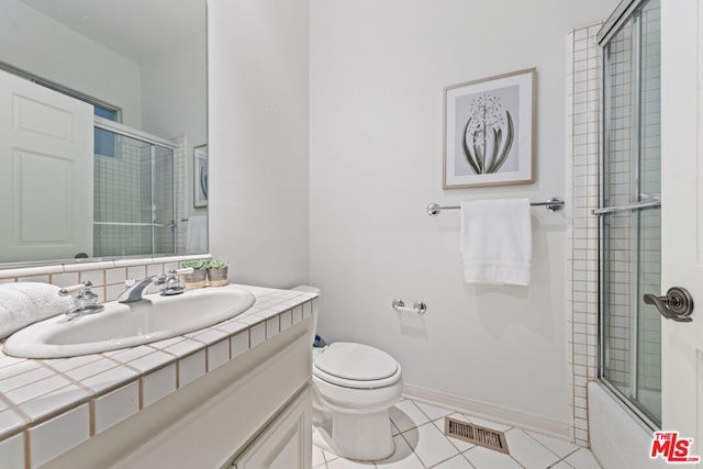 full bathroom featuring vanity, toilet, combined bath / shower with glass door, and tile patterned floors