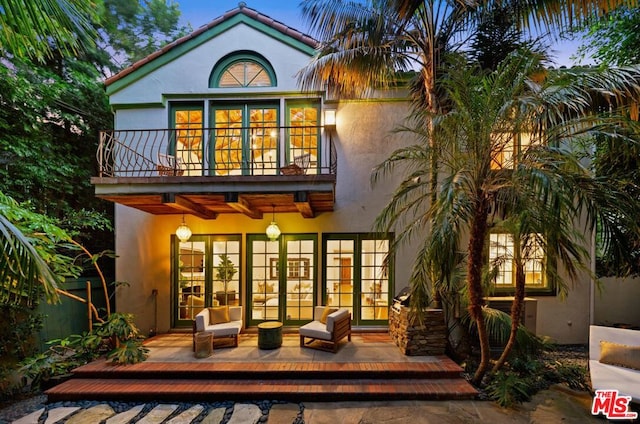 rear view of property featuring a balcony and an outdoor living space