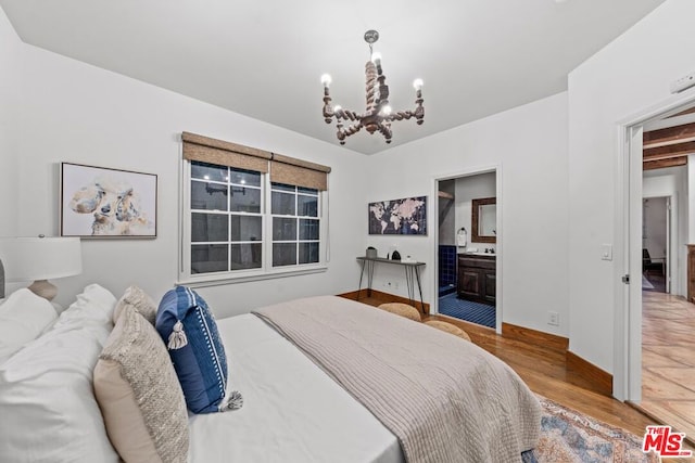 bedroom featuring an inviting chandelier, ensuite bathroom, and hardwood / wood-style floors