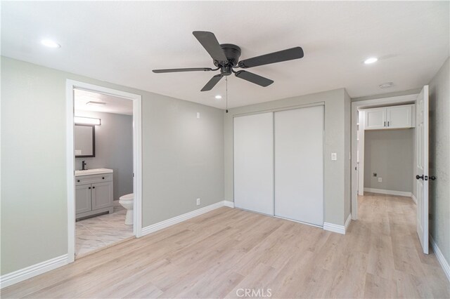 unfurnished bedroom featuring sink, ceiling fan, light wood-type flooring, connected bathroom, and a closet