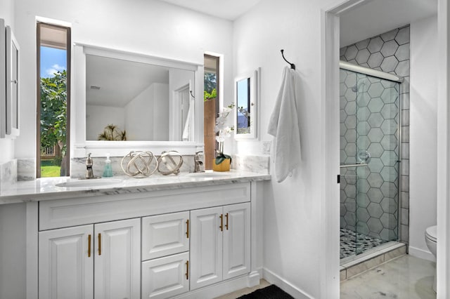 bathroom with a shower with door, toilet, plenty of natural light, and double sink vanity