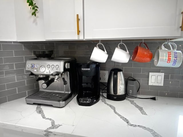 details with light stone counters, white cabinets, and backsplash