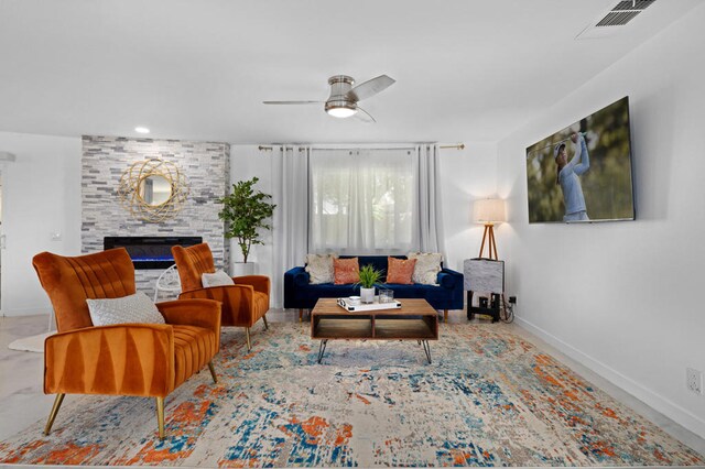 living room with a stone fireplace and ceiling fan