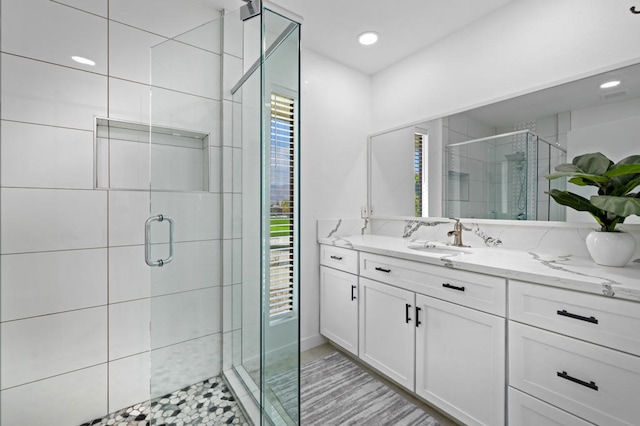 bathroom with a shower with shower door and vanity