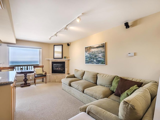 carpeted living room featuring rail lighting, a water view, and a tile fireplace