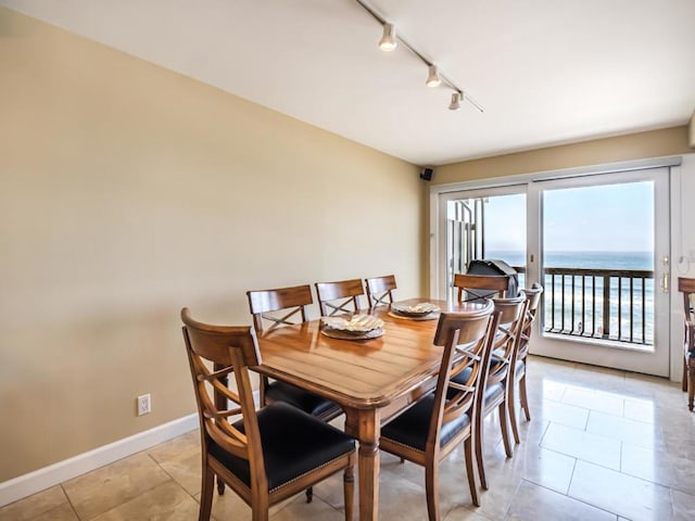 tiled dining space with rail lighting and a water view