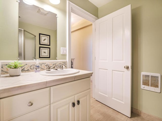 bathroom with tile patterned flooring, heating unit, an enclosed shower, and vanity