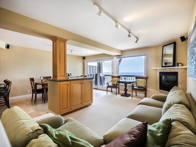 living room featuring decorative columns, rail lighting, light carpet, and a tiled fireplace