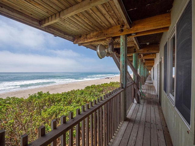 balcony with a water view and a view of the beach