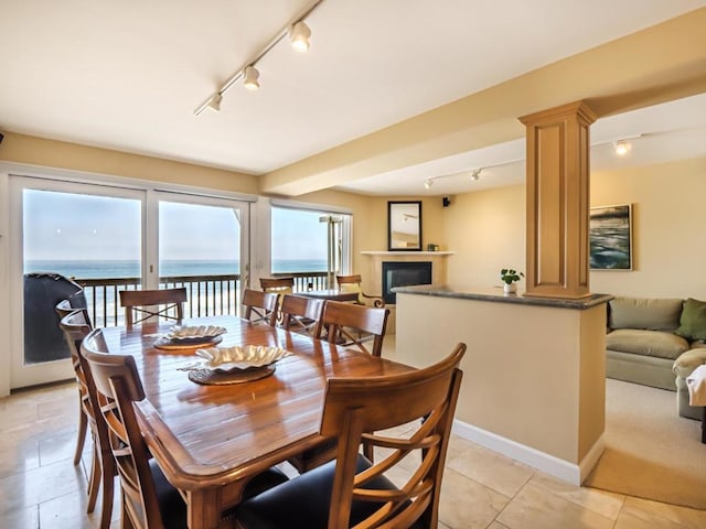 tiled dining room with a water view and decorative columns