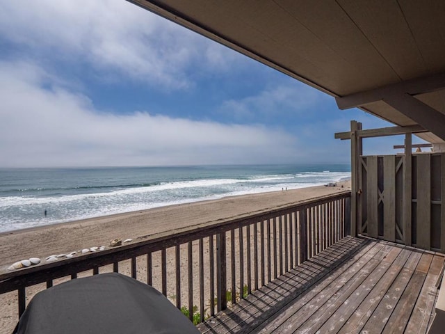 wooden terrace featuring a water view and a view of the beach