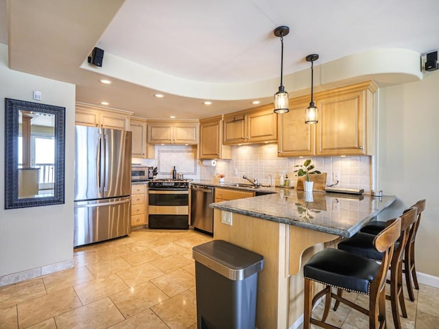 kitchen featuring kitchen peninsula, stainless steel appliances, dark stone countertops, pendant lighting, and sink