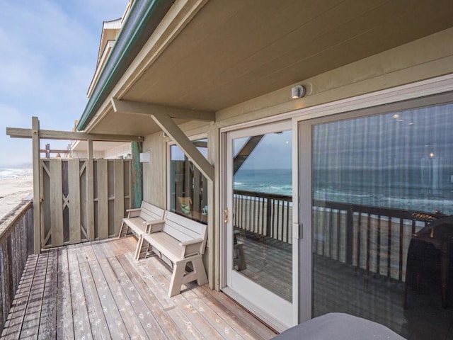 wooden terrace featuring a water view and a beach view