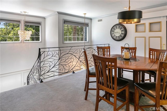 dining space with carpet floors, an inviting chandelier, and ornamental molding