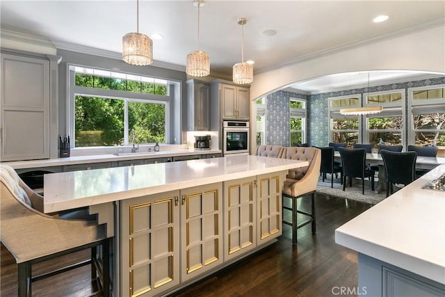 kitchen featuring a breakfast bar, dark wood-type flooring, oven, a spacious island, and hanging light fixtures