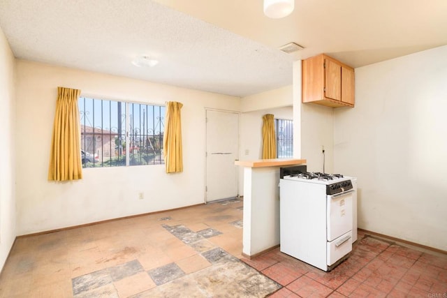 kitchen with light brown cabinets and white gas range oven