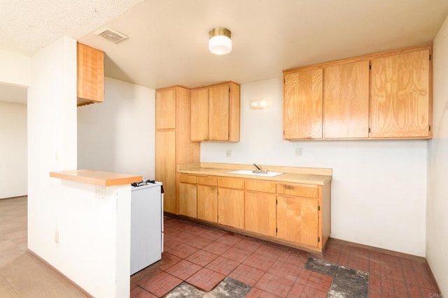 kitchen with kitchen peninsula, sink, white range, and light brown cabinets