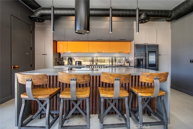 kitchen featuring a large island, a breakfast bar, black fridge with ice dispenser, and tasteful backsplash