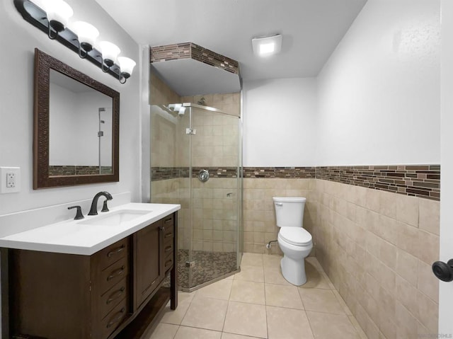 bathroom with tile patterned floors, walk in shower, vanity, tile walls, and toilet