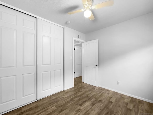 unfurnished bedroom with a textured ceiling, ceiling fan, a closet, and dark hardwood / wood-style floors