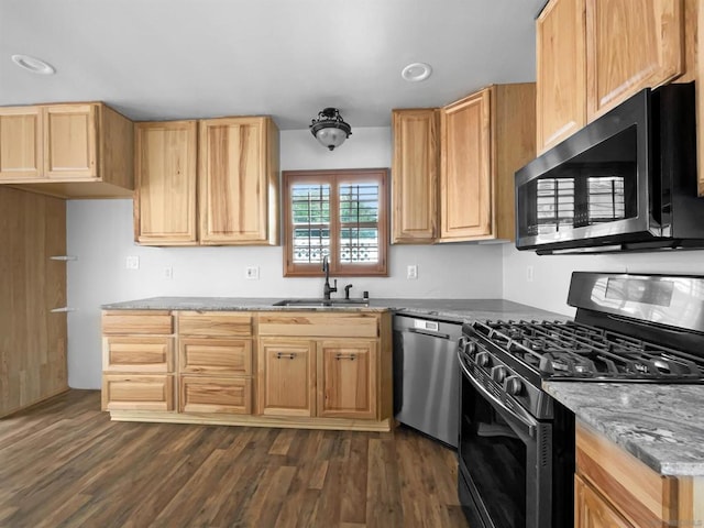 kitchen featuring light stone countertops, appliances with stainless steel finishes, dark wood-type flooring, and sink